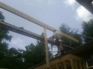 Carpenter setting a ridge beam over a new addition frame — Ice Dam Removal by Roofing Brothers in Wisner