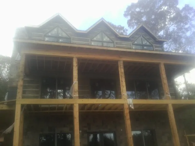 Dormers and porch framing on a large log home under construction — Roof Coating work by our crew in Wisner