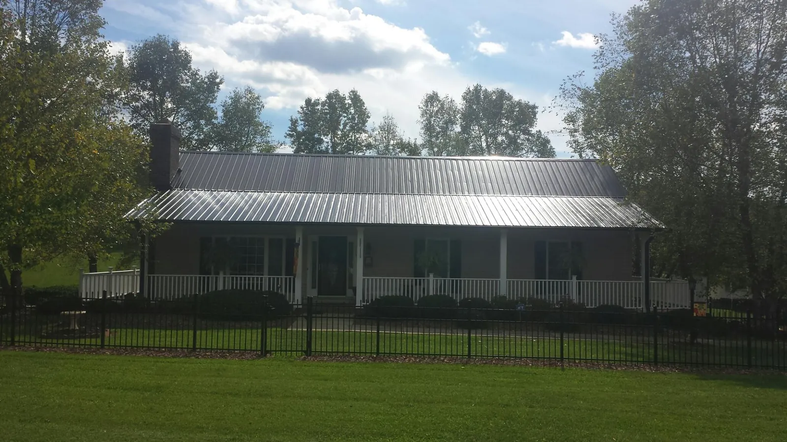 Gray metal roof on a brick ranch with a full width front porch — Gutter Guard Installation work by our crew in Wisner