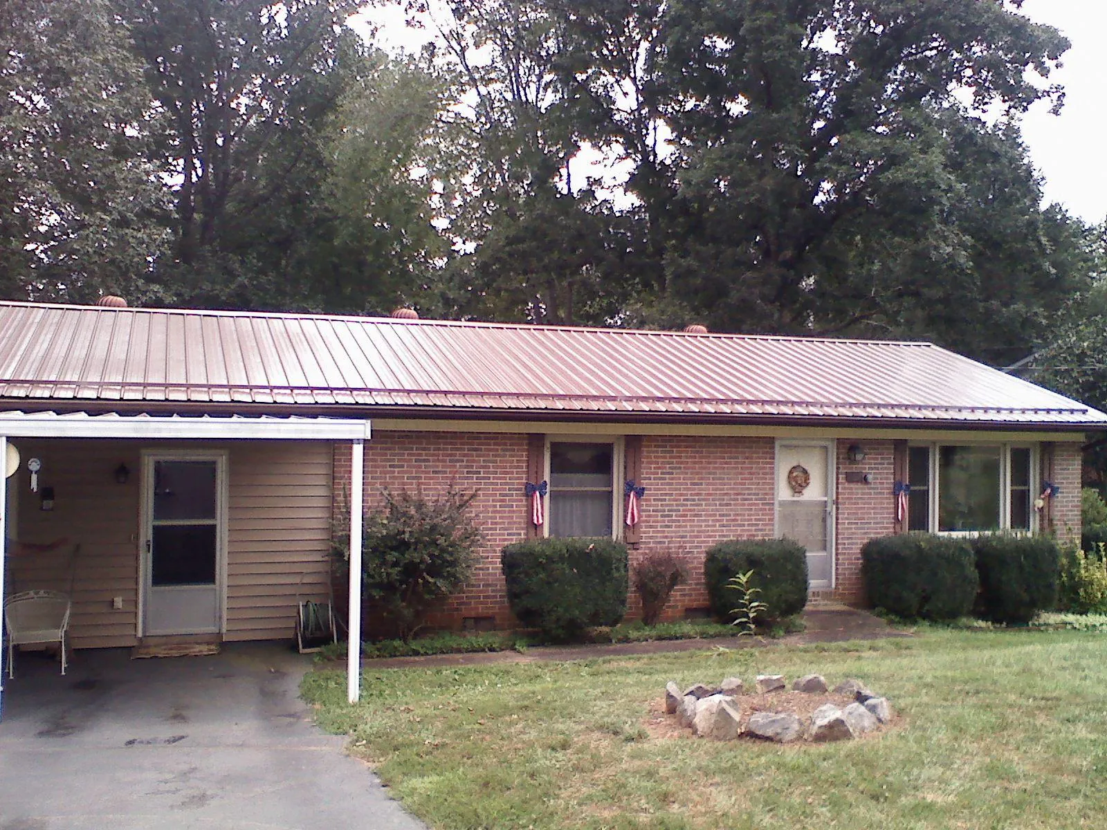 Bronze metal roof and carport on a brick ranch home — Roof Repair work by our crew in Wisner