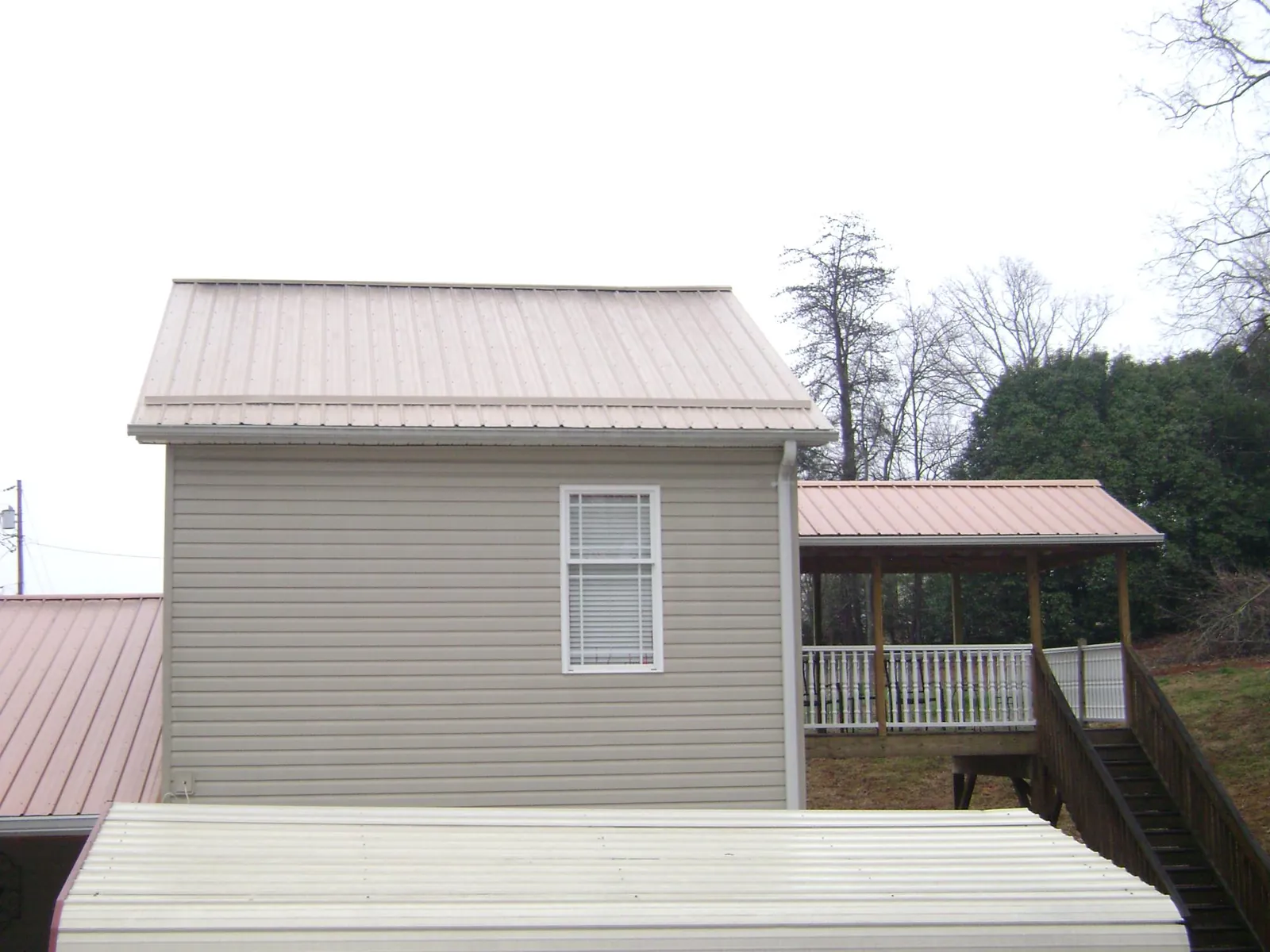 Tan metal roofs on a two story addition and attached porch in Wisner
